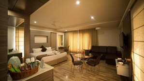 Ein modernes Hotelzimmer mit einem großen Bett, einer Essecke, einer Couch und einem Fernseher.