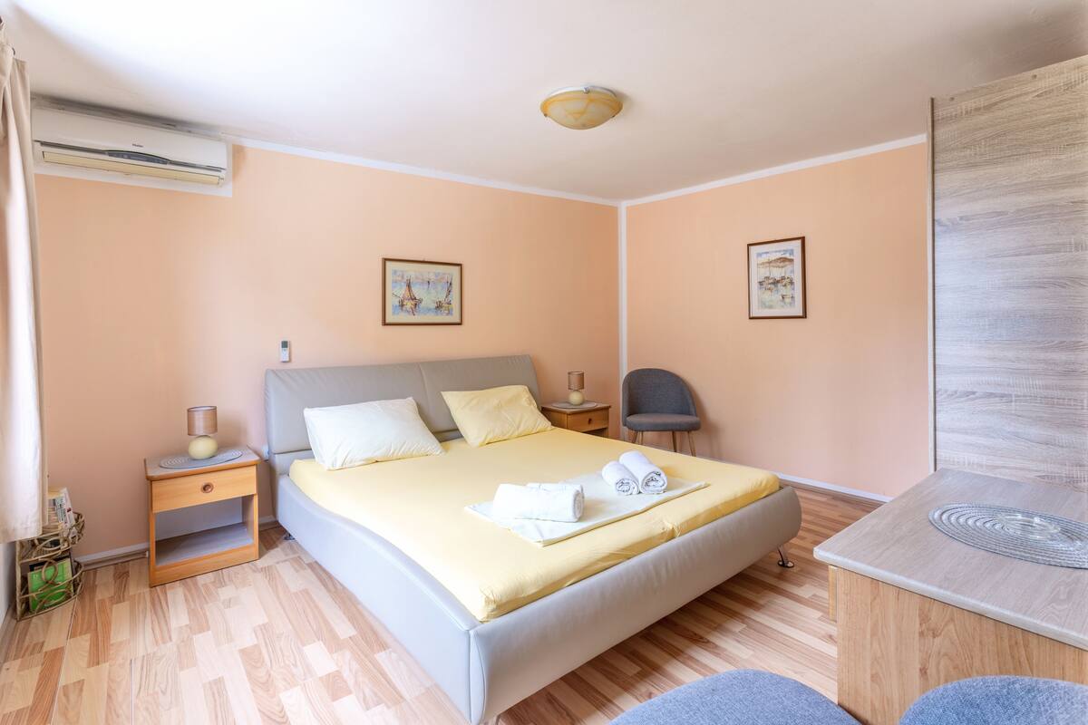 A neatly arranged bedroom with a bed, bedside tables, a chair, and a desk.