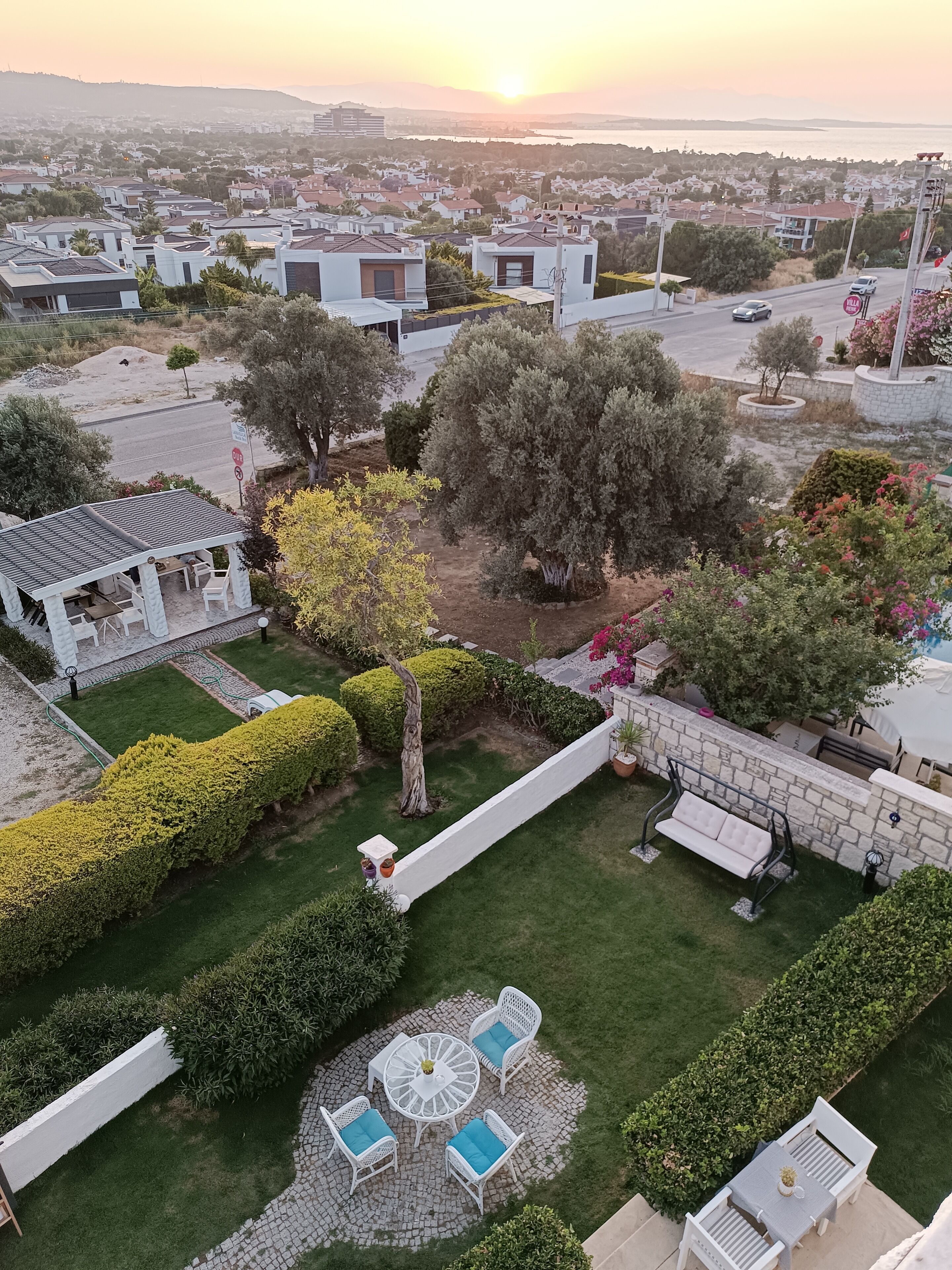 Un quartier résidentiel doté d’un patio, d’un espace salon extérieur et offrant une vue sur la mer au coucher du soleil.