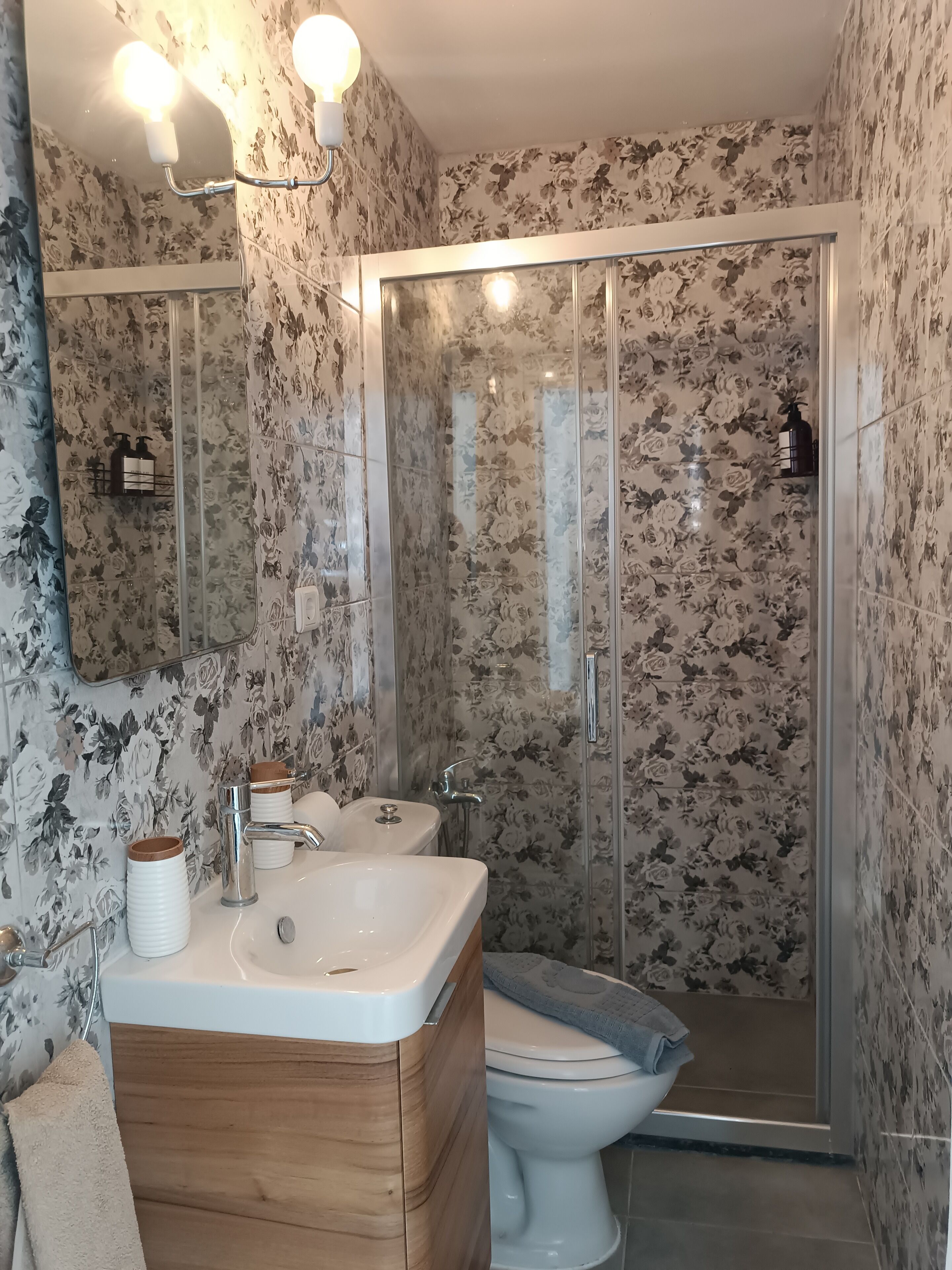 Un baño con tocador de madera, un lavamanos blanco, un inodoro y una cabina de ducha de cristal.
