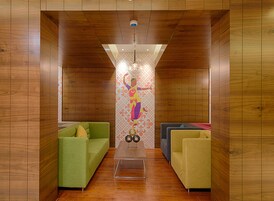 A modern room with wooden panel walls, a green sofa, a blue sofa, and a patterned wall decoration.