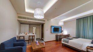 Una habitación de hotel con cama, escritorio, silla, sofá y televisión.
