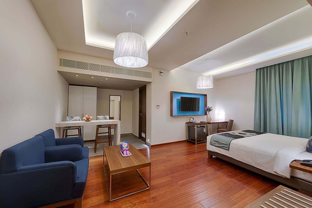 Une chambre d’hôtel comprenant un lit, un bureau, une chaise, un canapé et un téléviseur.
