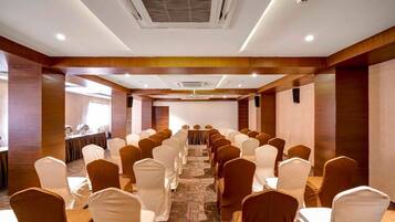 Un salón de conferencias con filas de sillas, una mesa larga y suelo alfombrado.