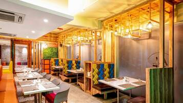 Un restaurant doté de nombreuses tables et de banquettes, avec des éléments décoratifs en bois et des luminaires suspendus.