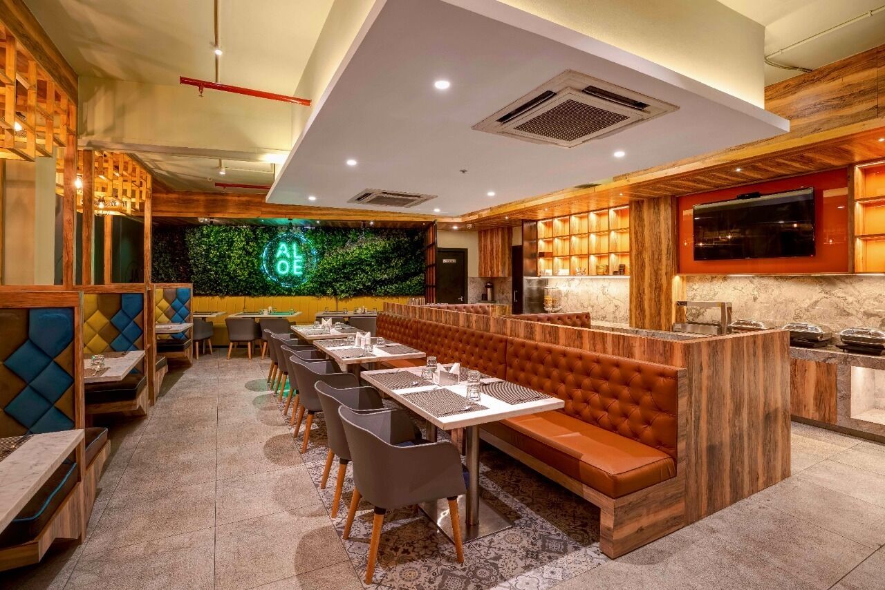 A restaurant with wooden booths, tables, and a neon sign.