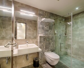 Een moderne badkamer met een douchecabine van glas, een wastafel met dubbele wastafel en een toilet.