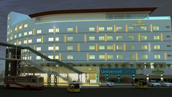 Een modern hotel met meerdere verdiepingen, een overdekte trap en een bordje met 'Universcell Sync'.