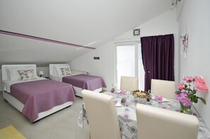 A bedroom with two beds, a dining table with chairs, and a window with curtains. - Apartments Roza (Seget)