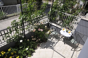 A balcony with a table and chairs, surrounded by a metal fence and potted plants. - Apartments Roza (Seget)