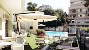 Área de piscina no terraço, com mobiliário externo e vista para edifícios ao redor.