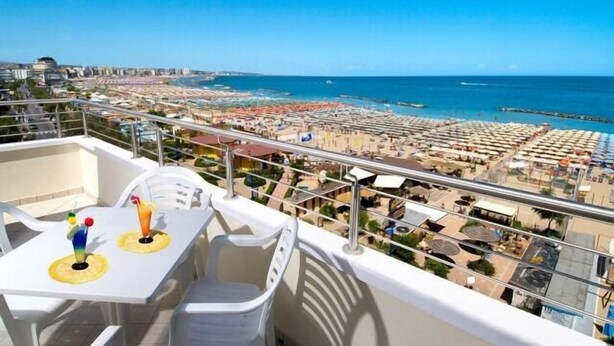 Varanda com mesa e cadeiras com vista para a praia e o horizonte urbano.