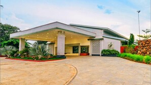 A modern building with a covered entrance, a landscaped driveway, and a stone wall. - Trance Greenfields Resort and Convention Centre (Hyderabad)