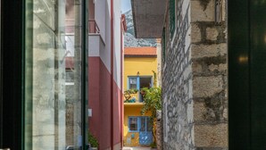 Un callejón estrecho con un edificio amarillo, una puerta azul y un muro de piedra.