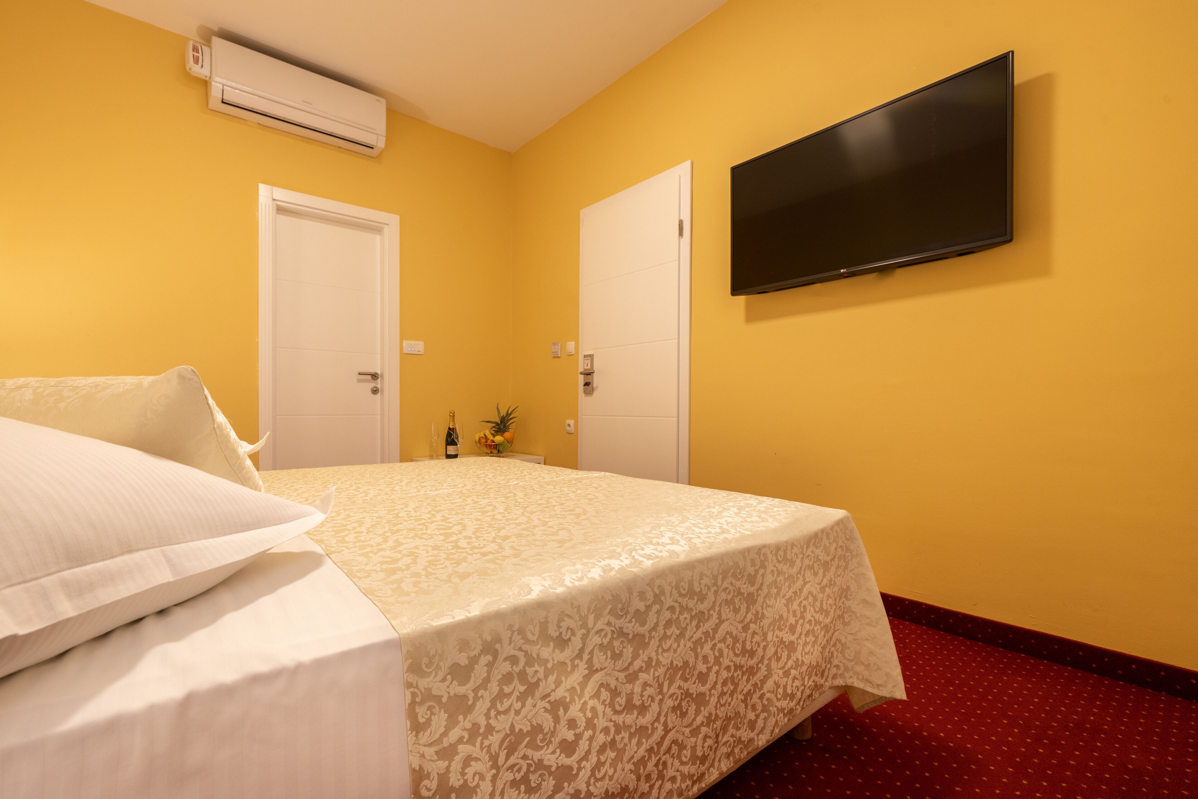 Habitación de hotel con cama, televisor de pantalla plana en la pared y dos puertas.