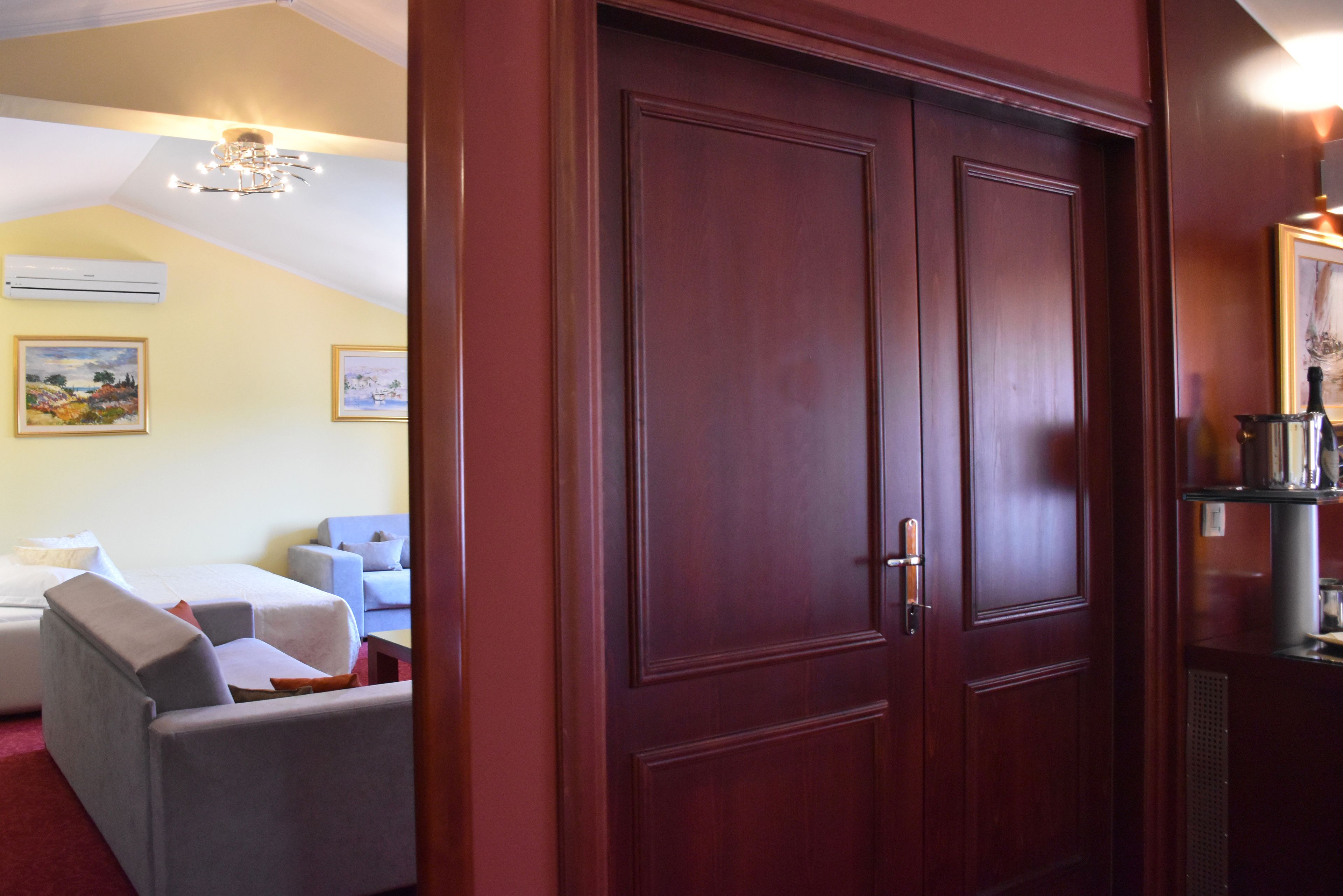 A hotel room with a double door, a bed, a desk, and two armchairs.