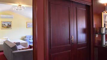 A hotel room with a double door, a bed, a desk, and two armchairs.