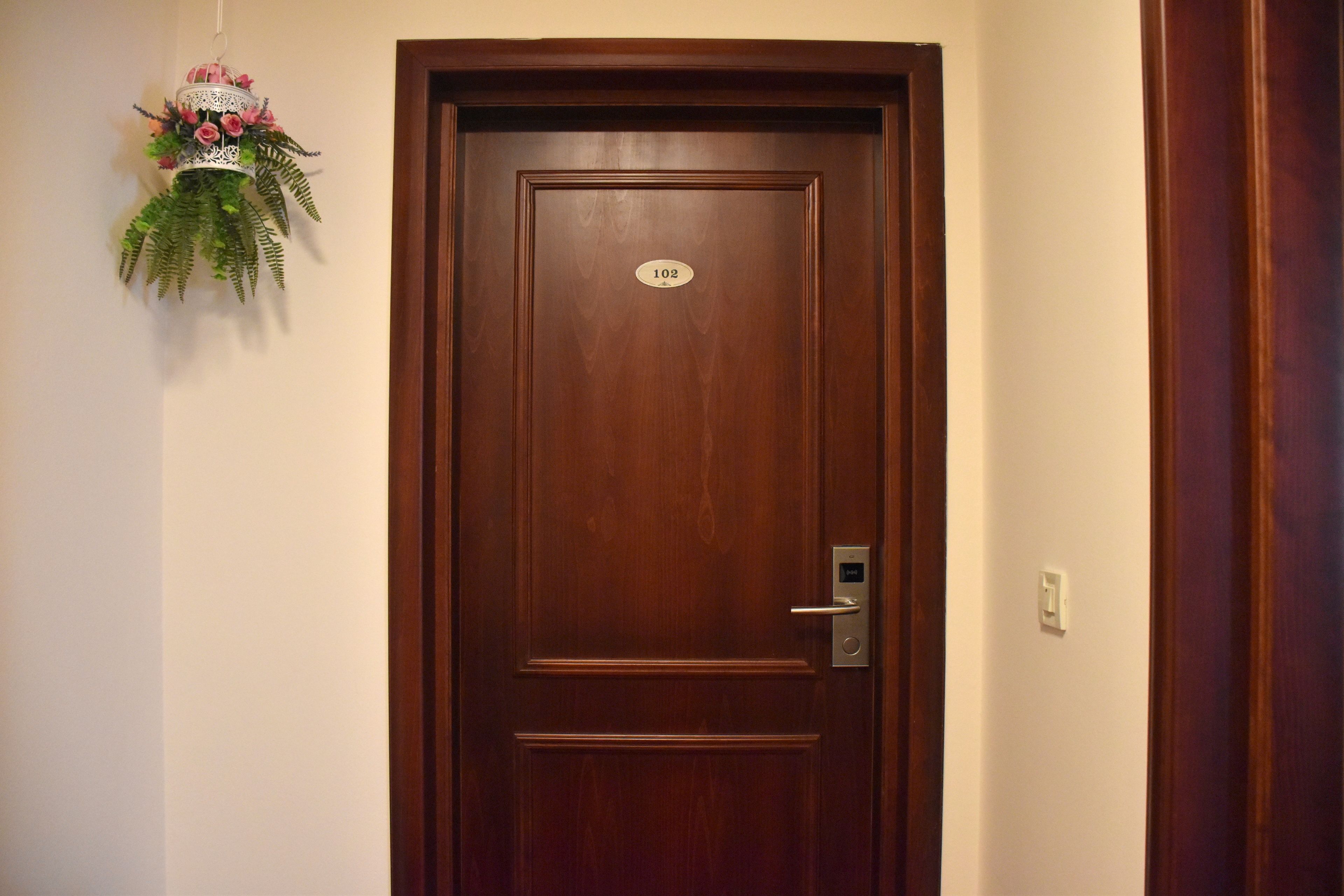 Une porte en bois avec une plaque de numéro, un interphone et un élément décoratif fixé au mur.