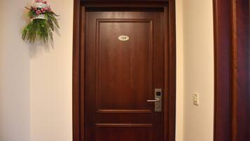 Une porte en bois avec une plaque de numéro, un interphone et un élément décoratif fixé au mur.