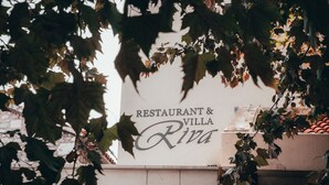 Señalización para un restaurante y una villa llamados Riva, rodeados de follaje.