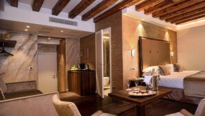Una habitaci ón de hotel moderna con techo de madera, una cama grande, un área de descanso con una mesa y un baño visible a través de una puerta abierta.
