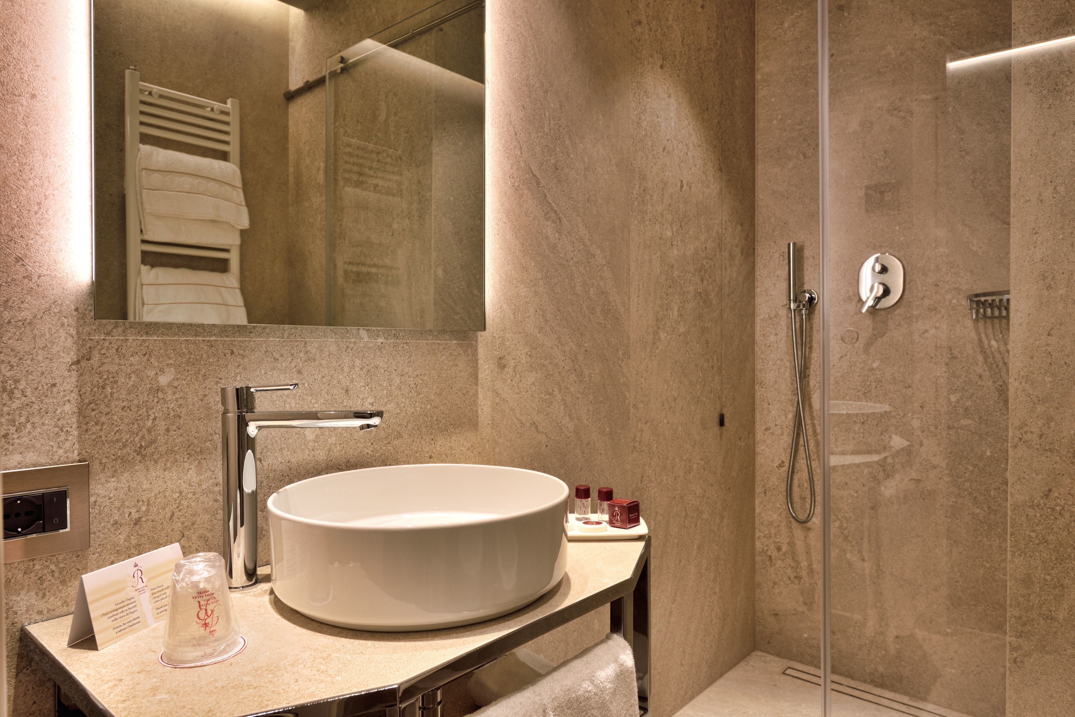 Un baño moderno con un lavamanos grande, espejo y ducha.