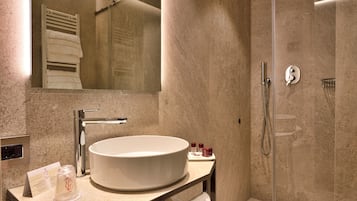 Un baño moderno con un lavamanos grande, espejo y ducha.