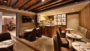 Un restaurante moderno con vigas de madera en el techo, una zona de bar y diferentes disposiciones de asientos.