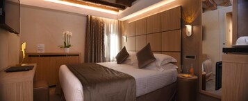 Quarto de hotel com cama, mesa de cabeceira, abajur e espelho.