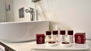 A bathroom with a large white bathtub, a marble wall, and a tray with various toiletries.