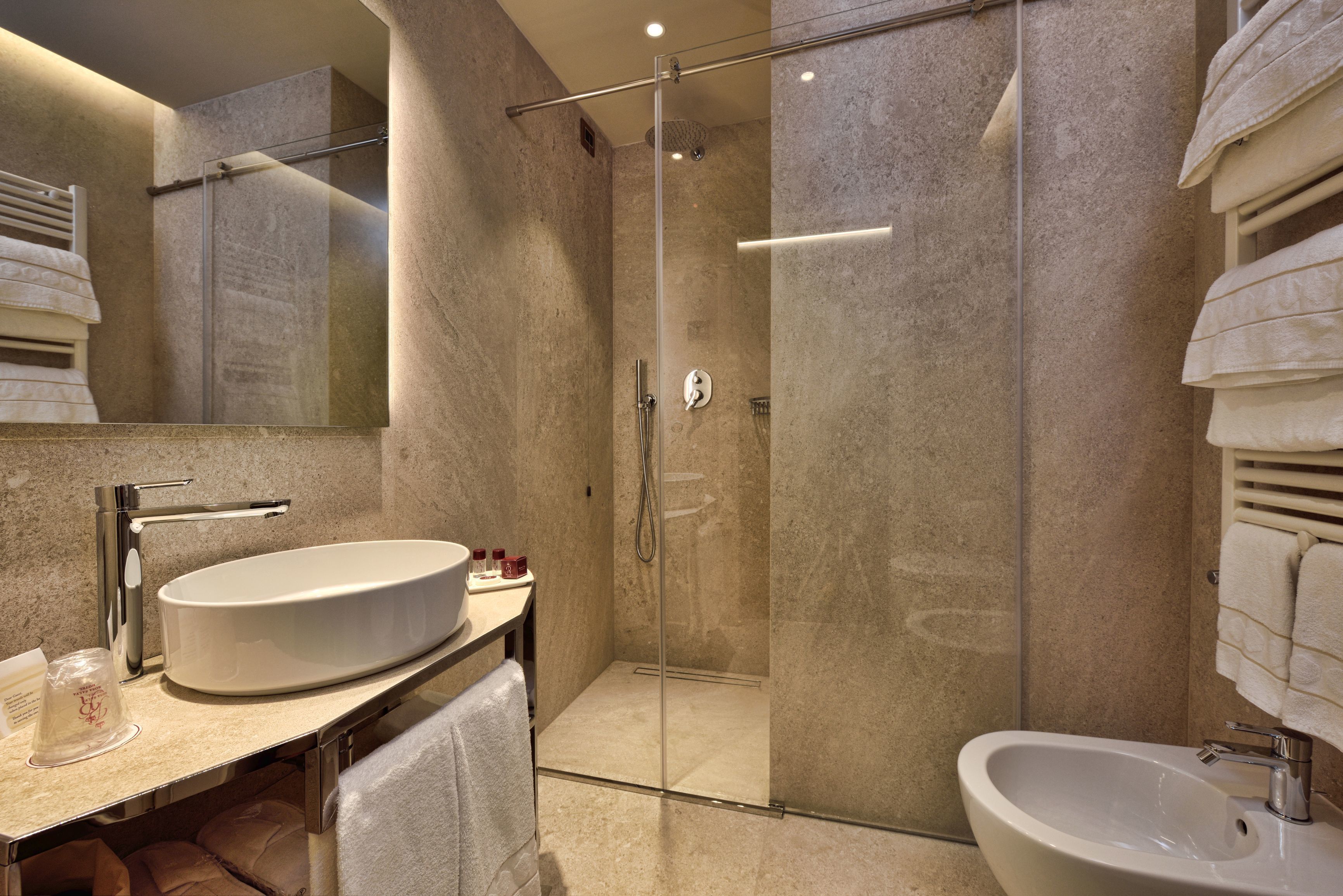 A modern bathroom with a glass-enclosed shower, a large sink, and a separate basin.