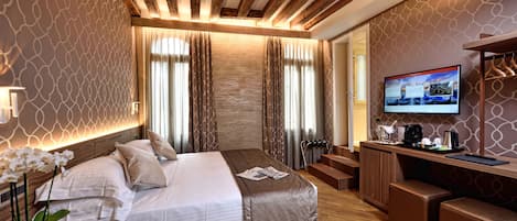 Quarto de hotel moderno com uma cama grande, uma escrivaninha e uma televisão.