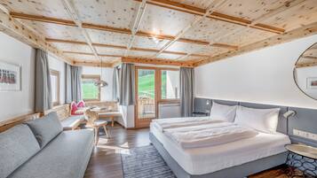 Een moderne hotelkamer met een houten plafond, een groot bed, een zithoek, een bureau en uitzicht op het omliggende landschap.