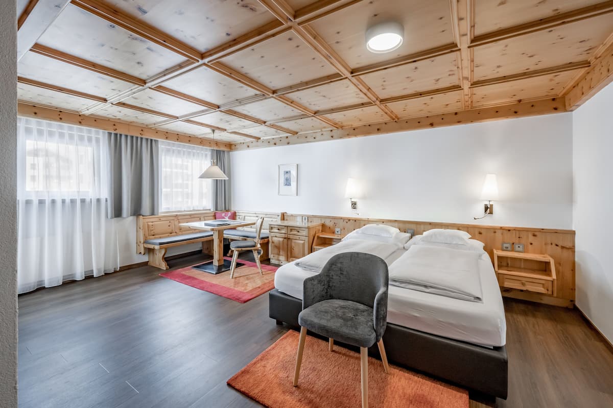 Ein modernes Hotelzimmer mit Holzboden, einem Bett, einem Schreibtisch und einem Stuhl.