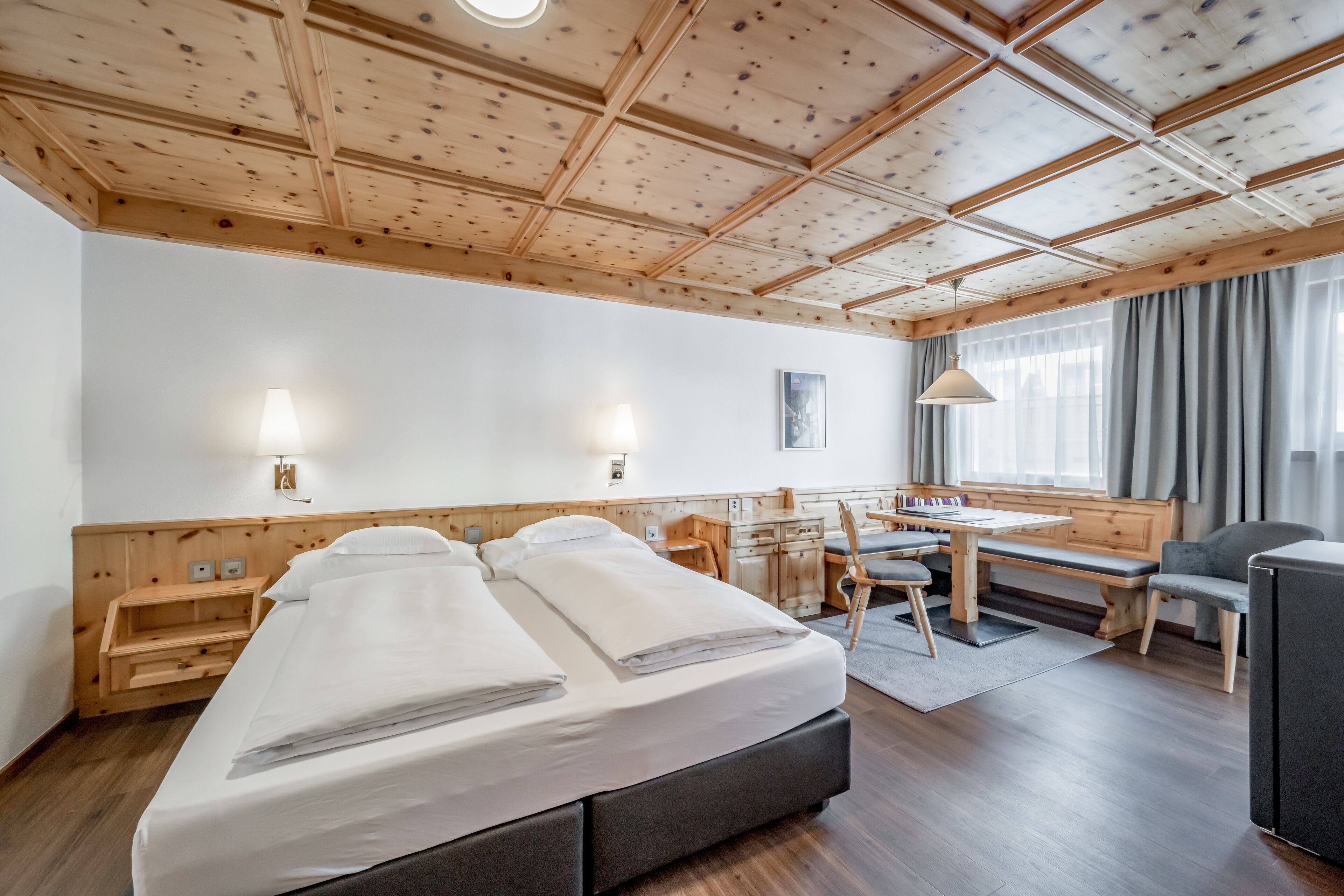 A hotel room with a large bed, a desk, and a chair.