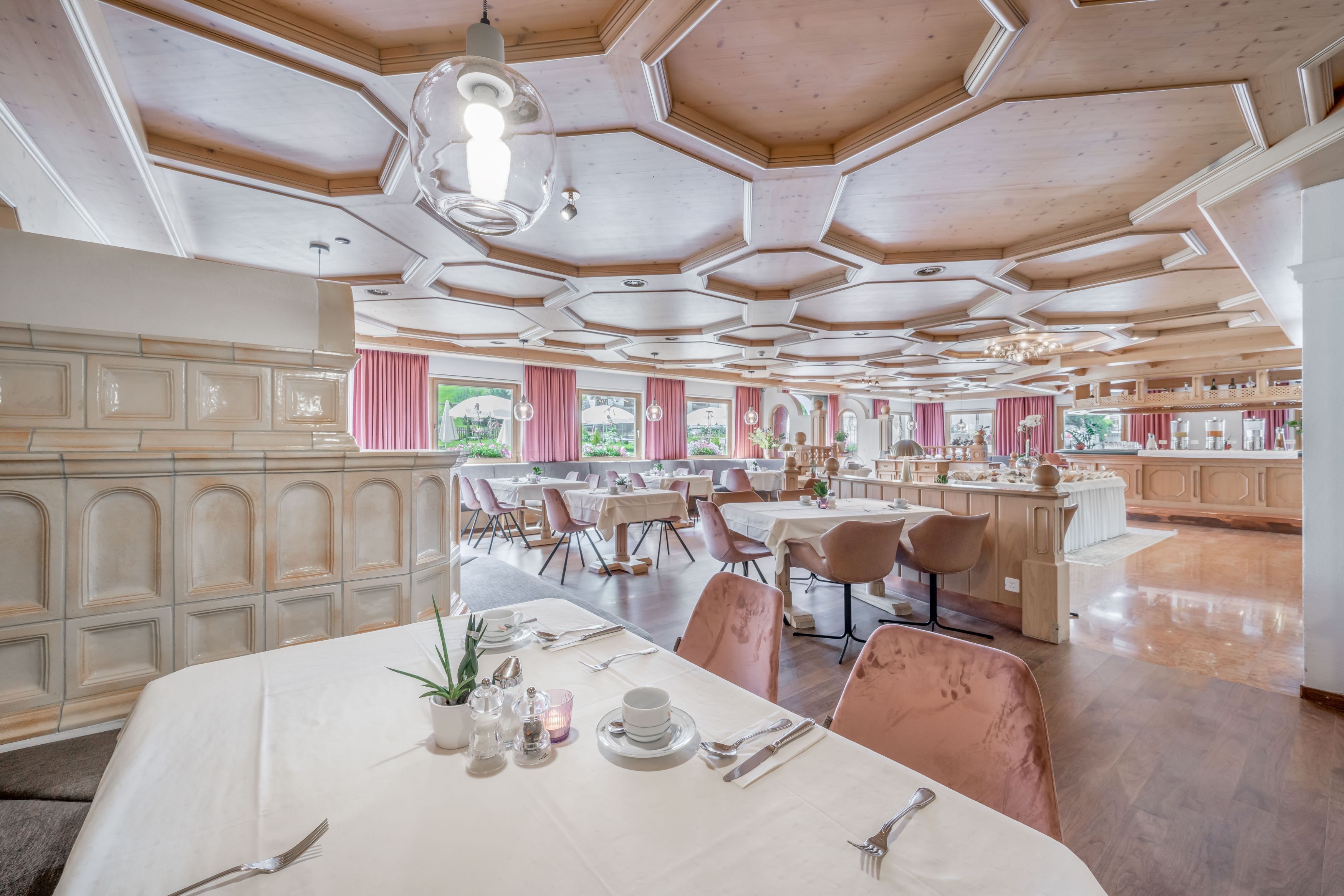 Un comedor espacioso con diseño de techo hexagonal, ventanas amplias y vistas al jardín.
