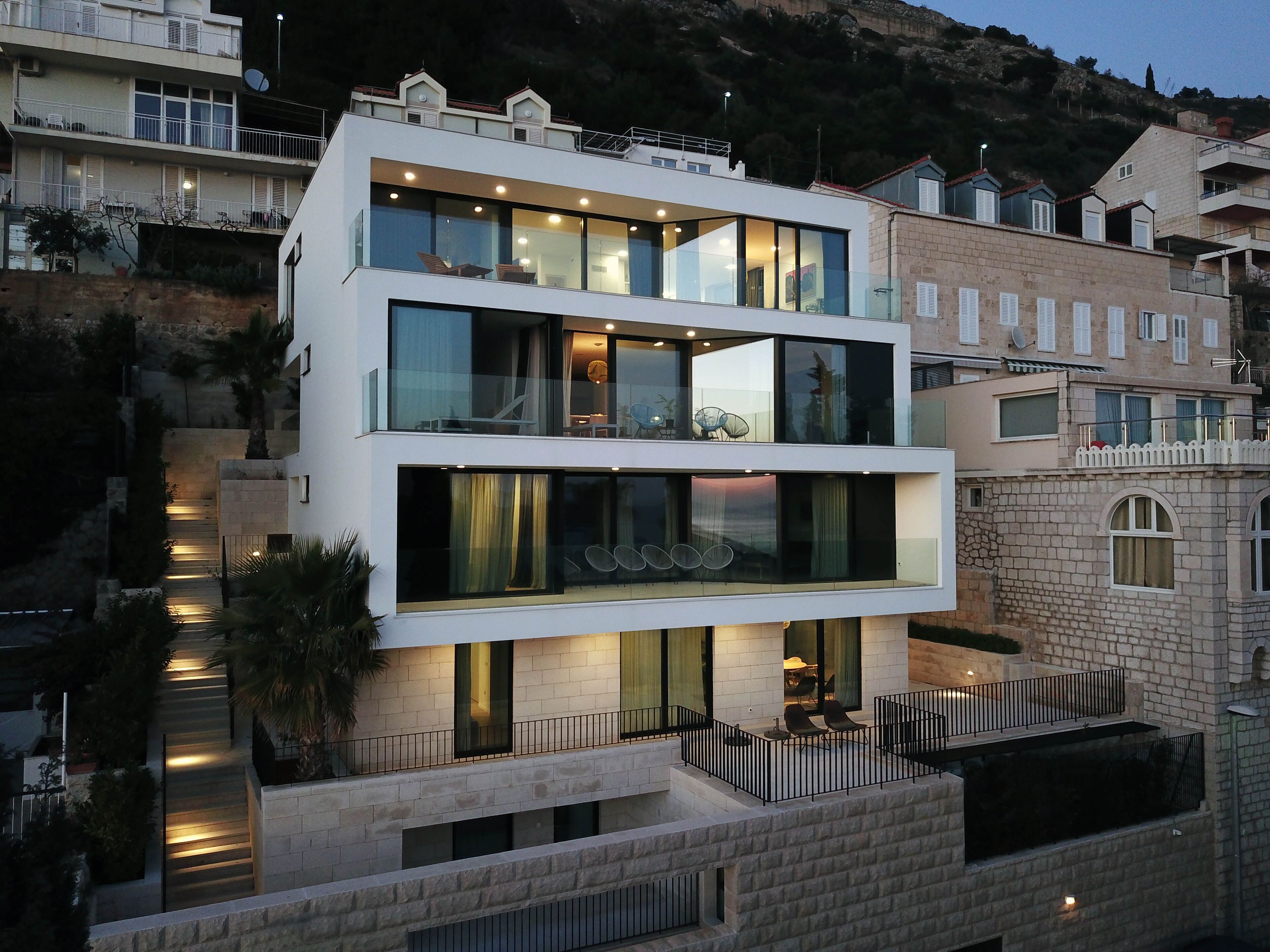 A modern multi-story building with balconies, large windows, and a stone facade.