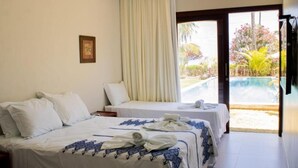 A hotel room with two beds, a large window with a view of a pool and garden, and a door leading to an outdoor area. - Pousada San Giovanni (Japaratinga)