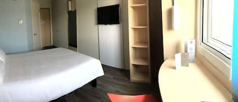 Una habitación de hotel con cama, televisor, armario y ventana.