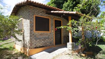 Una pequeña casa de ladrillo con techo de tejas, puerta principal y ventana.