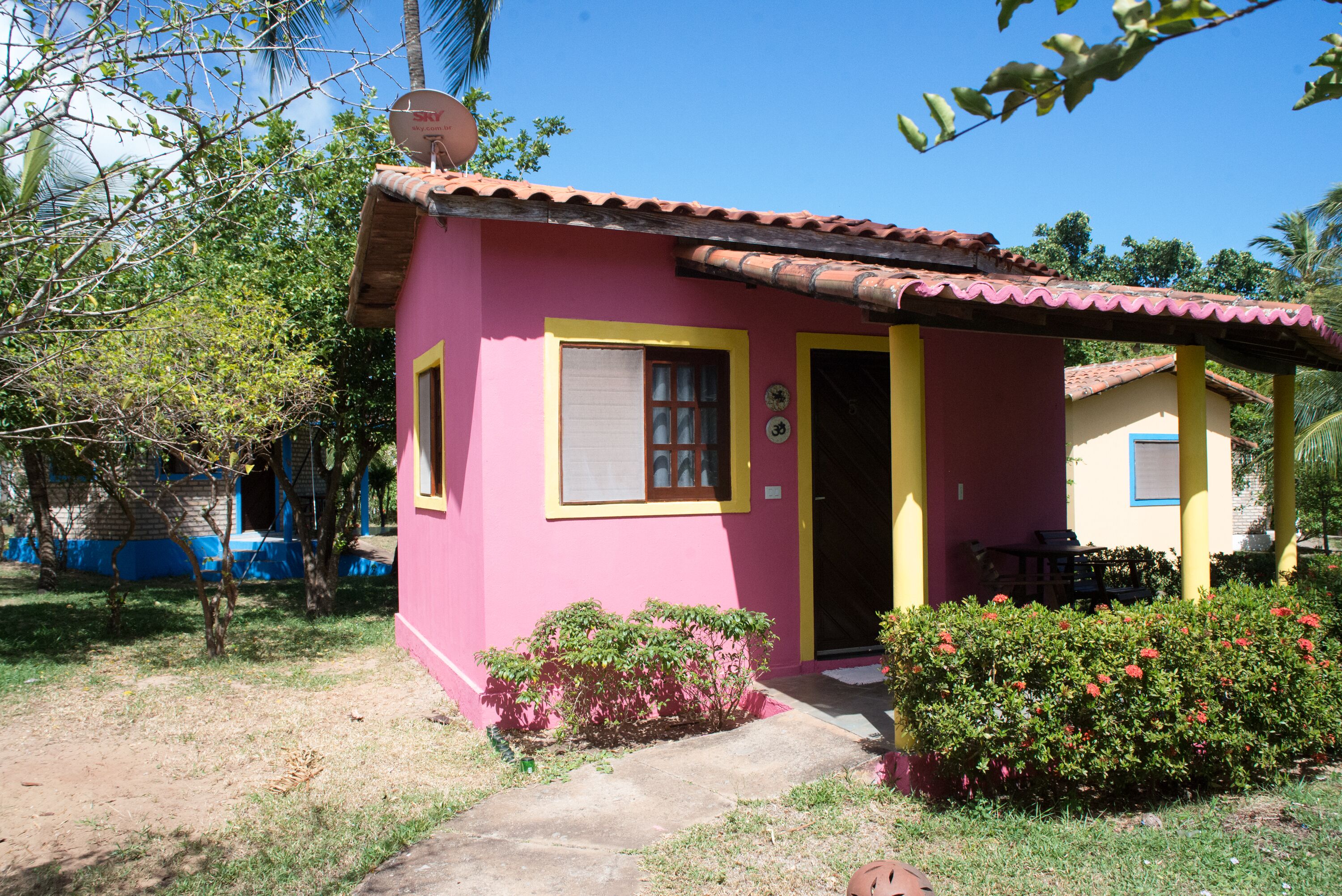 Ein kleines rosa Haus mit Ziegeldach, einer Tür und einem Fenster.