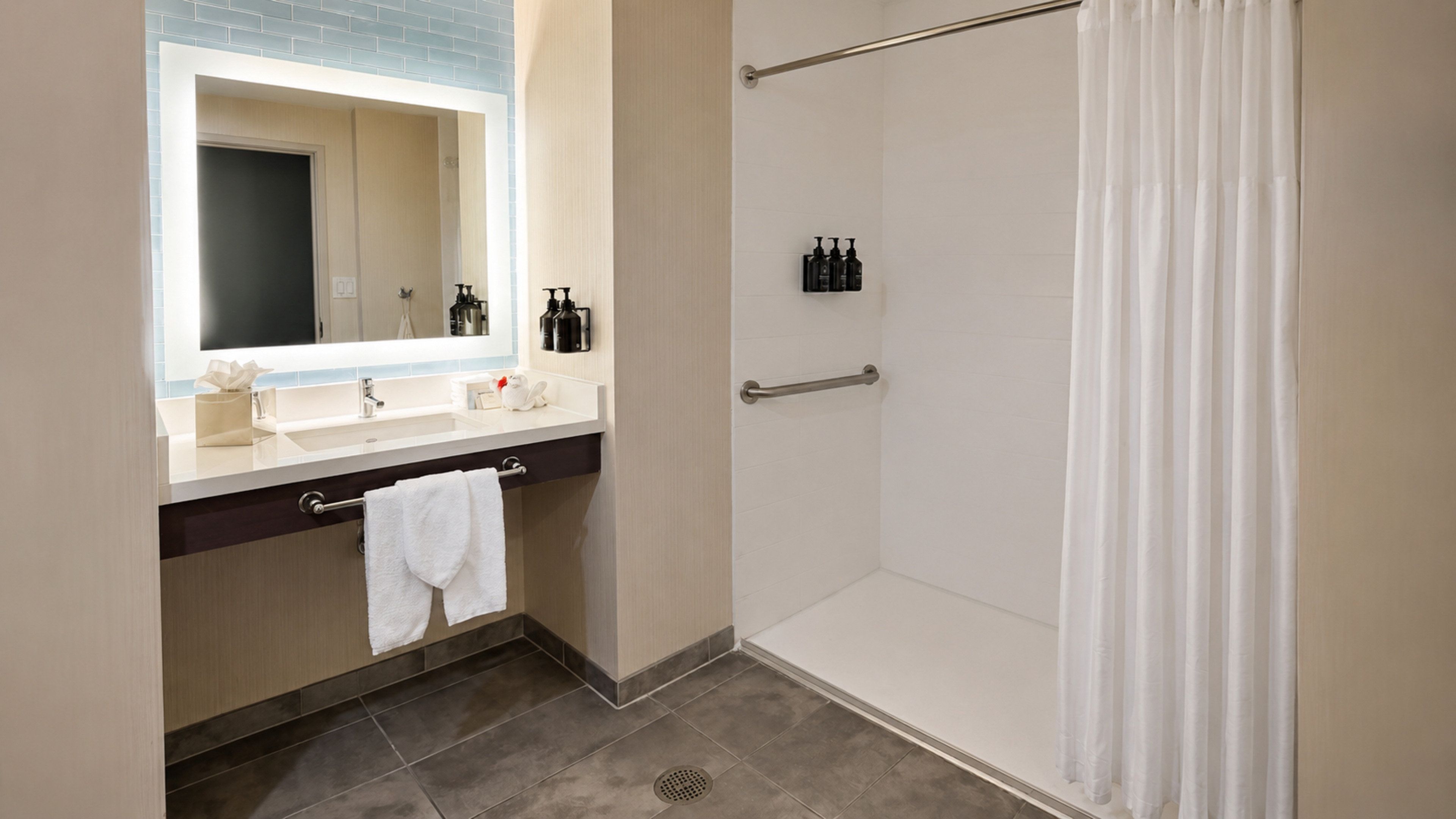 A bathroom with a shower, a sink, and a mirror.