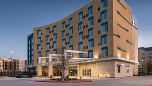 Un hôtel moderne à la façade incurvée, doté de nombreuses fenêtres et d’une entrée imposante.