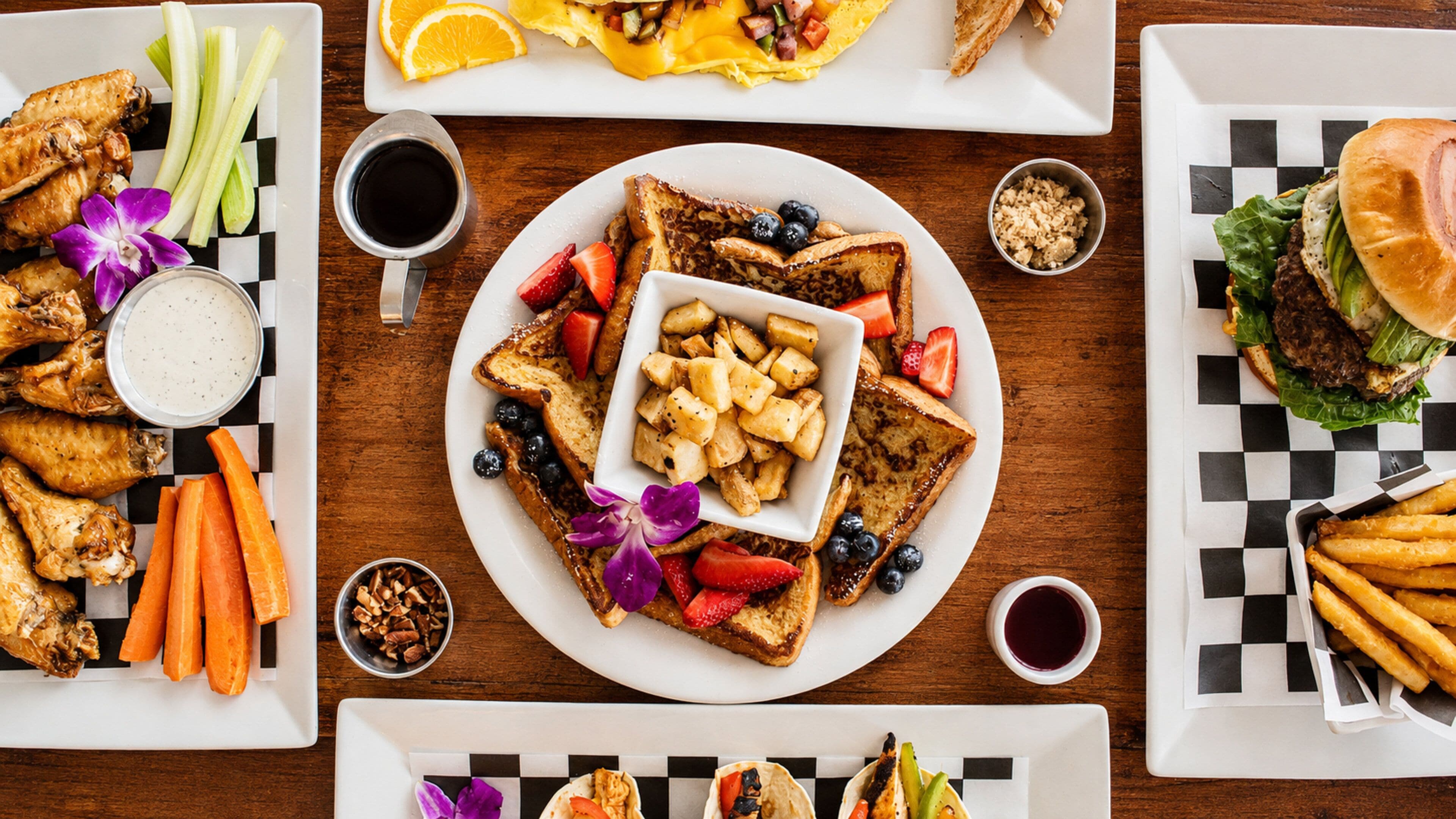 Une variété d’aliments pour le petit-déjeuner, notamment des toasts, des fruits et un hamburger, disposés sur une table en bois.