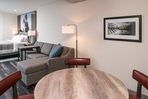Une chambre d’hôtel avec un lit, un canapé, une table à manger et une lampe.