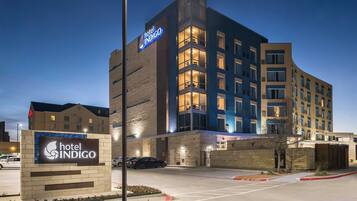A hotel with a prominent sign, a parking lot, and a clear sky.