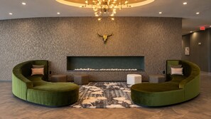 Un hall d’entrée avec un canapé vert aux lignes courbes, un tapis à motifs et une décoration murale représentant un crâne de taureau.