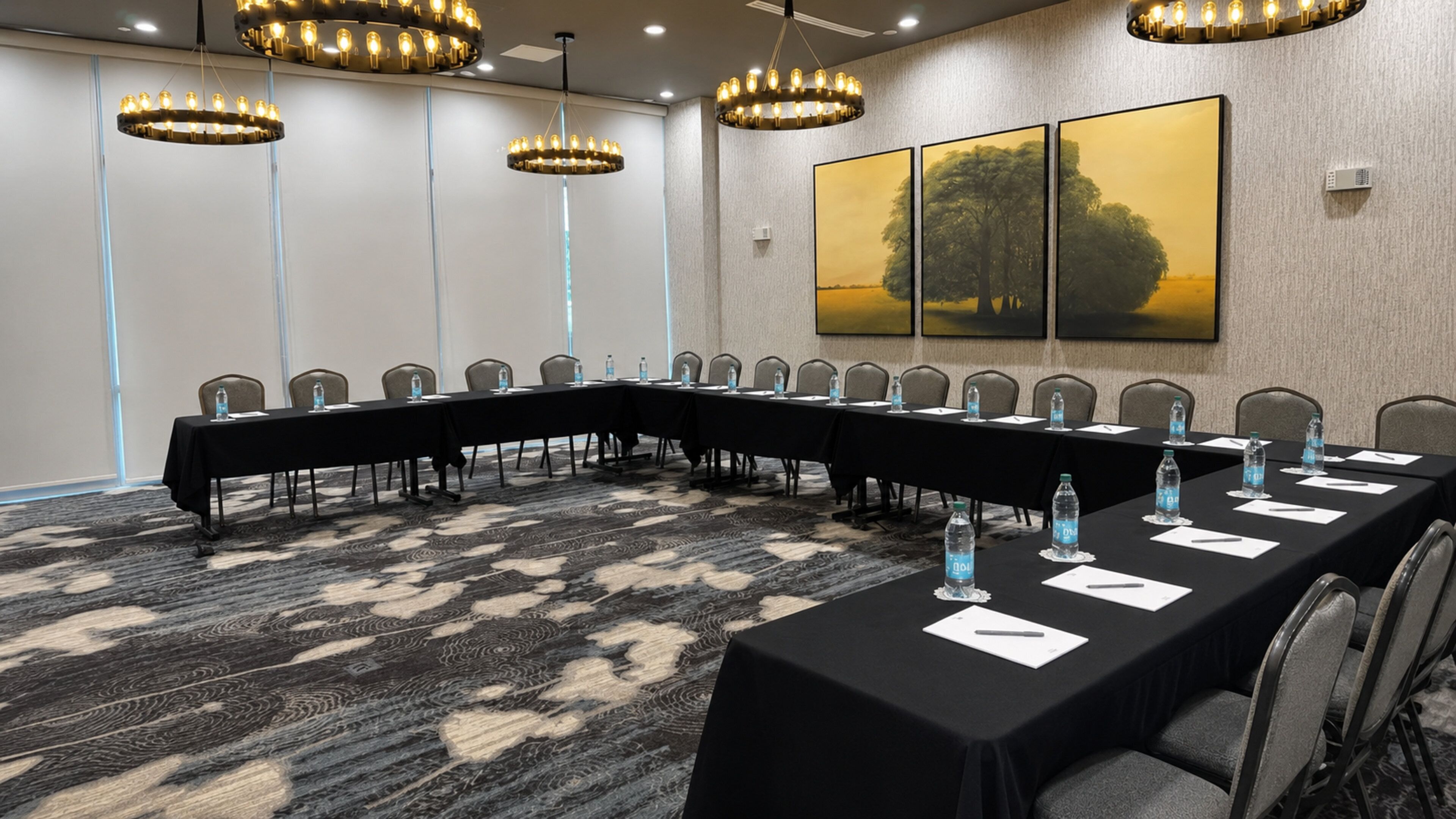 A conference room with a long table, chairs, water bottles, and a chandelier.