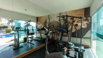 Una palestra moderna con diverse attrezzature per esercizi, una grande finestra e un poster motivazionale al muro.