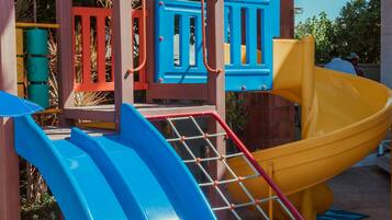 A playground with two slides, a climbing structure, and a covered seating area.